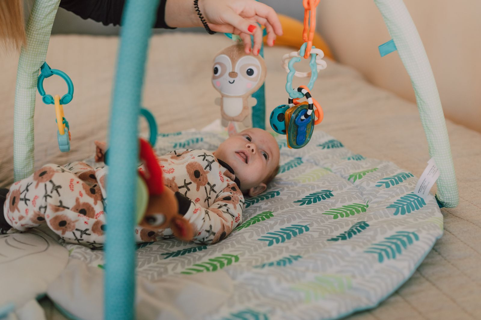 Baby lying on a play mat interacting with hanging toys